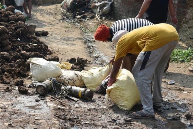 Villagers use sacks filled with sand to protectively surround parts of a projectile intercepted by the Indian Army in Wadala Bhattewad village near Amritsar, India