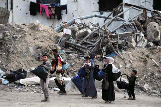 Palestinians walk carrying bags in Gaza City after an Israeli army evacuation warning