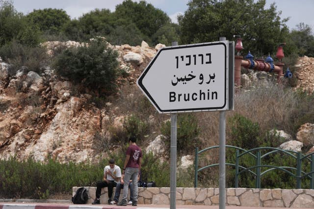 Young Israeli settlers sit outside the West Bank settlement of Bruchin