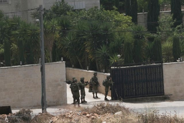 Israeli soldiers search a Palestinian village next to the West Bank settlement of Bruchin 