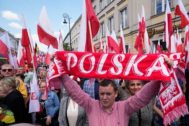 A person holding a Polish scarf during a rally