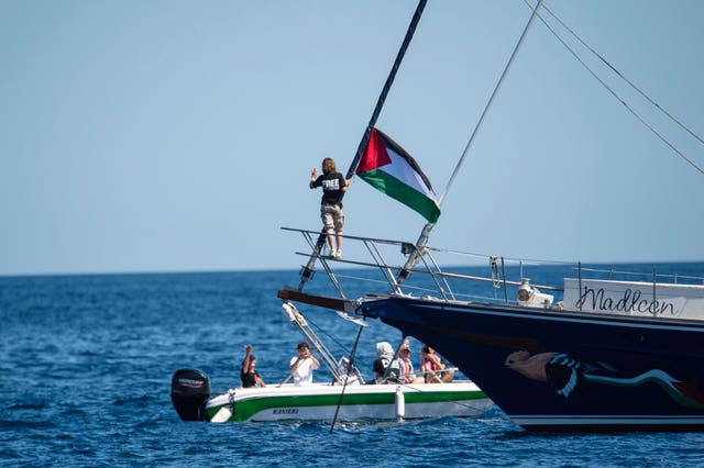 Climate activist Greta Thunberg stands near a Palestinian flag on the Madleen