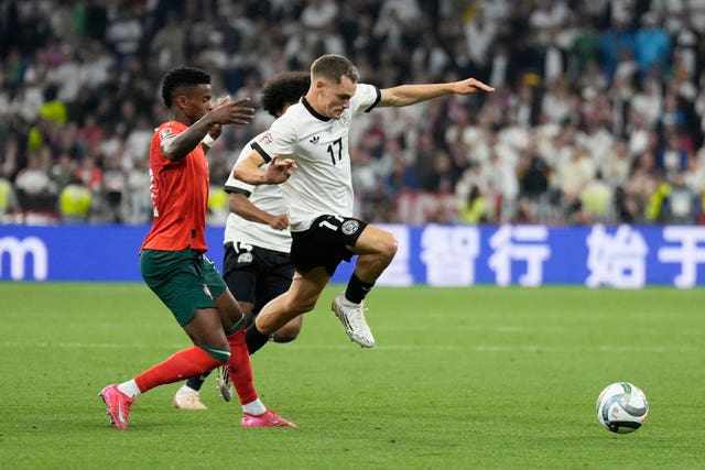 Germany's Florian Wirtz jumps over a tackle from Portugal's Nelson Semedo
