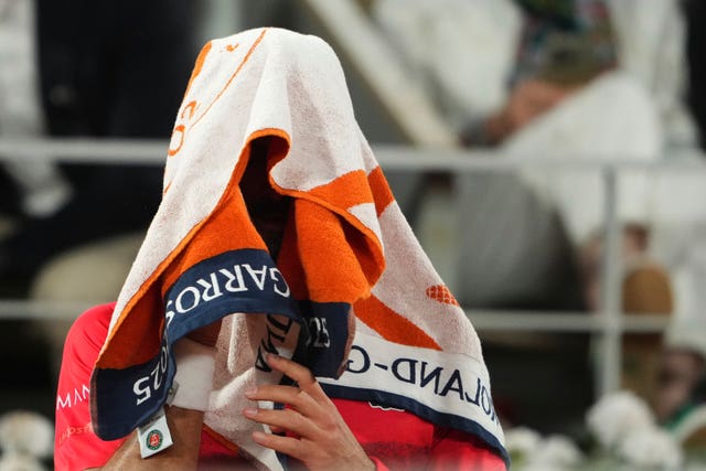 Novak Djokovic sits on a chair with a towel over his head