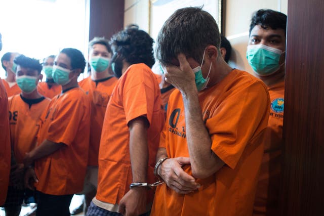 Australian national identified only as P.R., front right, who is handcuffed together with an Indian national identified as H.V., reacts as they are presented to the media with other drug suspects following their arrests