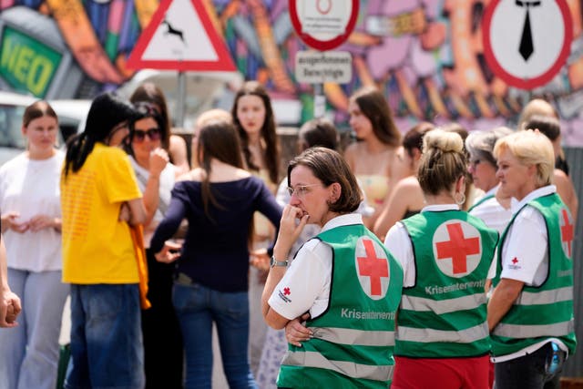 Medical helpers stand outside the school where a former student opened fire