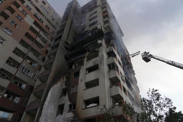 A firefighter stands on a crane at the scene of an explosion at a residence compound after Israeli attacks in Tehran