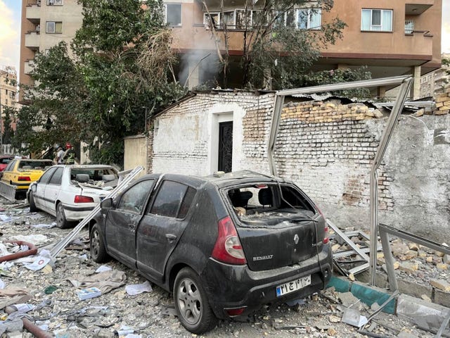 Debris from an apartment building is seen on top of parked cars after a strike in Tehran, Iran, early on Friday