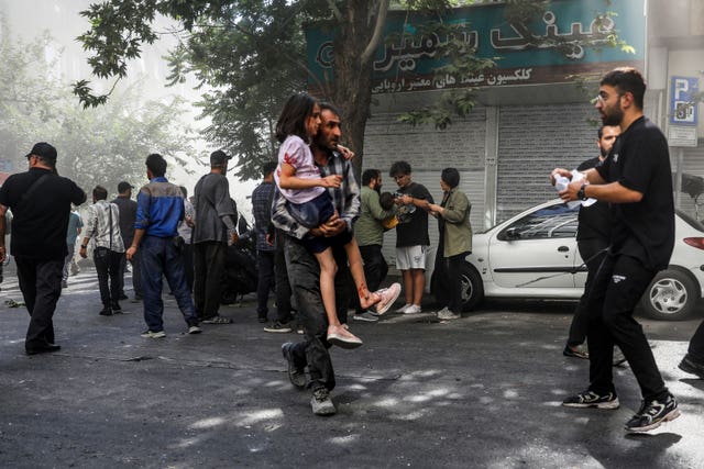 A man carries a wounded girl after an explosion in downtown Tehran