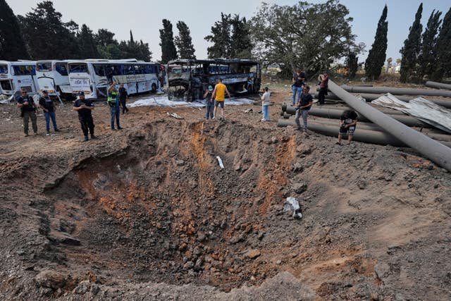 Israeli security forces inspect a site hit by a missile launched from Iran