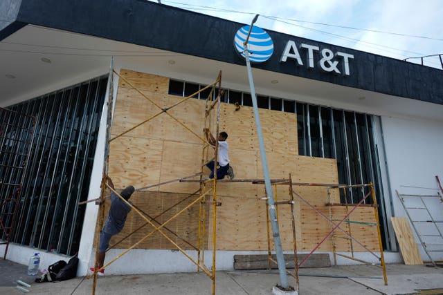 Workers in Acapulco board up a shop as they prepare for the arrival of Hurricane Erick