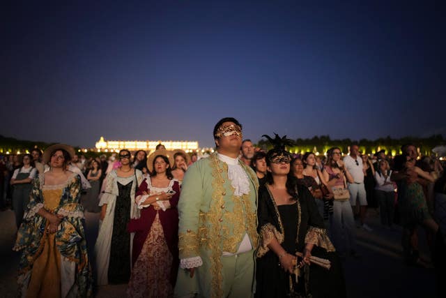 Costumed guests watch fireworks in the gardens of Versailles