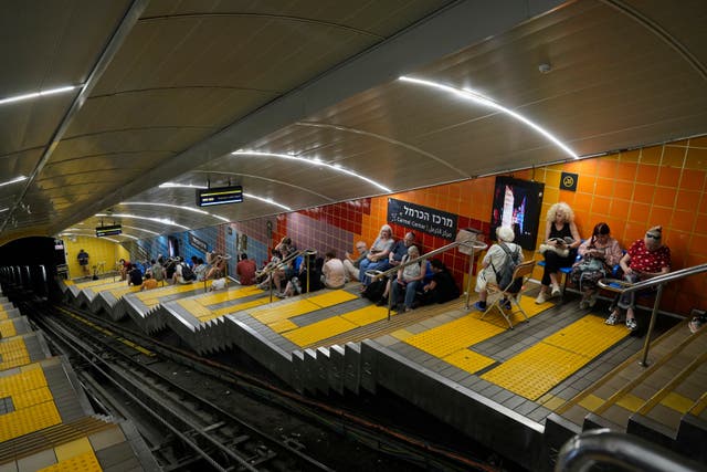 People take shelter in an underground metro station as air raid sirens warn of incoming Iranian strikes in Haifa, Israel