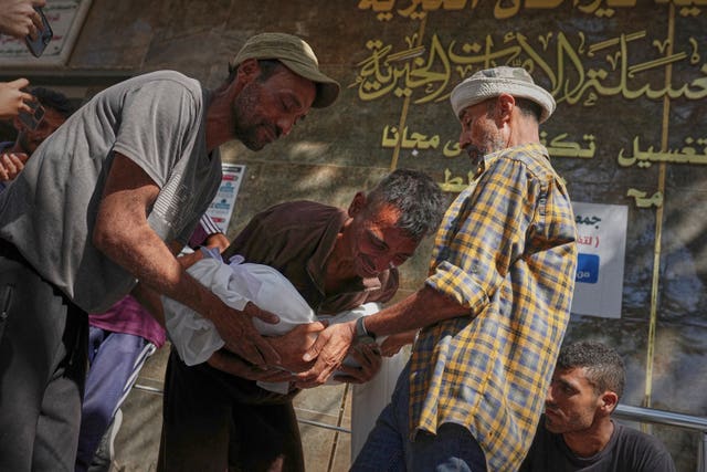 A man carries the wrapped body of a child in Gaza