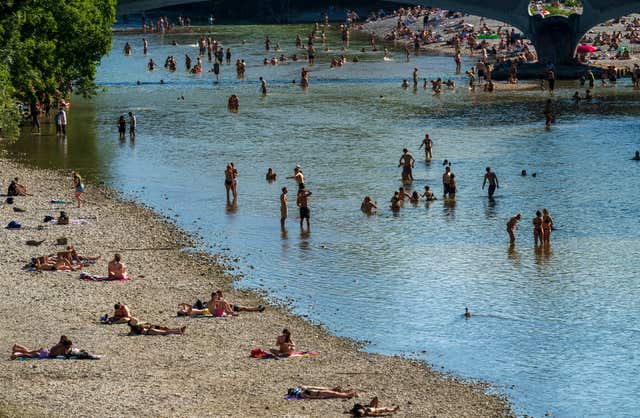 People enjoy the waters of the Isar around the Kabelsteg in Munich, Germany