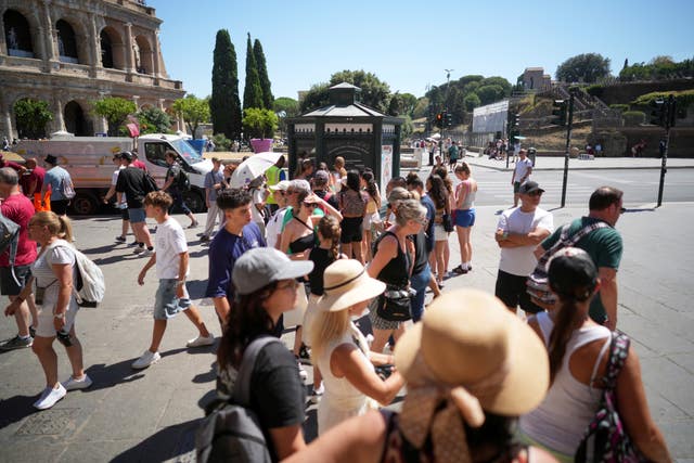 People stand in a line in front of a public fresh drinking water kiosk to drink and refill their water bottles in Rome 
