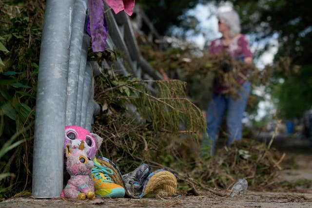 Lost items sit at a bridge as a volunteer cleans up debris after the flood in Kerrville, Texas 