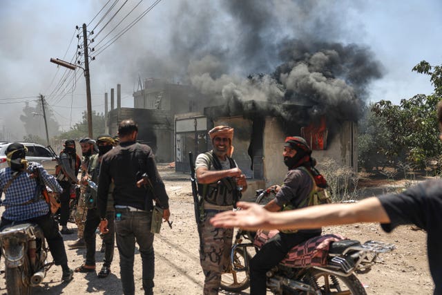 Bedouin fighters gather in front of a burning shop