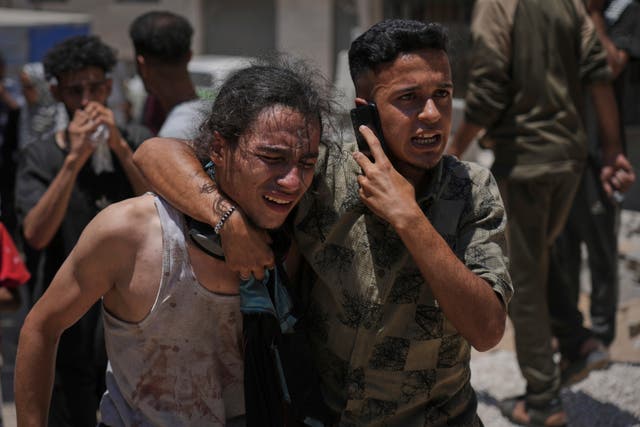 Palestinians react after carrying the bodies of those killed while trying to reach aid trucks entering northern Gaza through the Zikim crossing with Israel, at Shifa Hospital in Gaza City, on Sunday 
