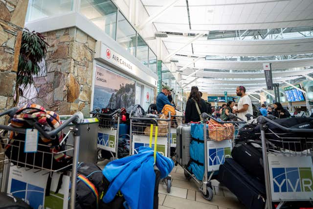 People wait outside an Air Canada check-in at Vancouver International Airport 
