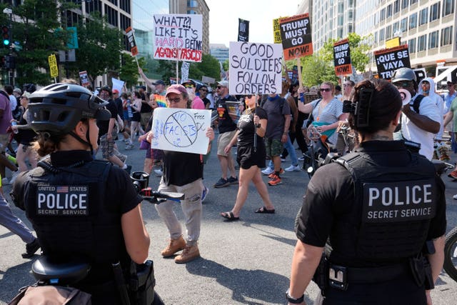 Police watch as activists carrying signs march to the White House
