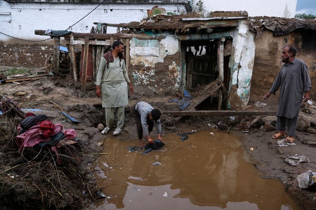 Villagers collect items in the rubble of their partially damaged in Pir Baba, an area of Buner district, in the north-west of Pakistan