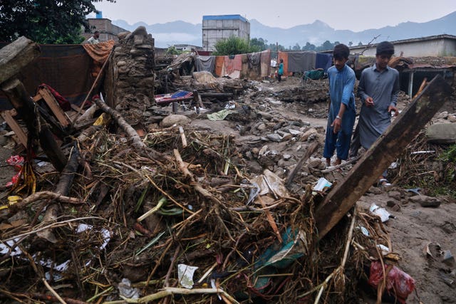 Villagers collect items in the rubble of their partially damaged home in Pir Baba, an area of Buner district, in the north-west of Pakistan
