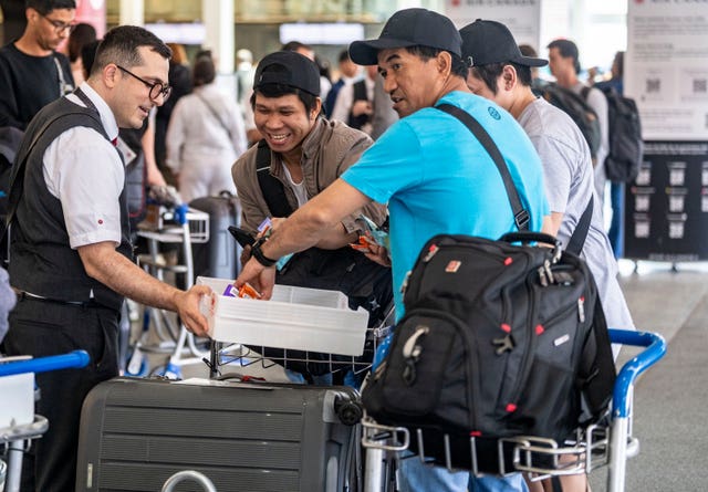 An Air Canada employee hands out snacks to travellers waiting for a flight 
