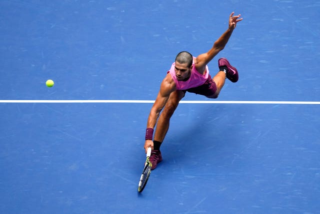 Carlos Alcaraz lunges for a backhand