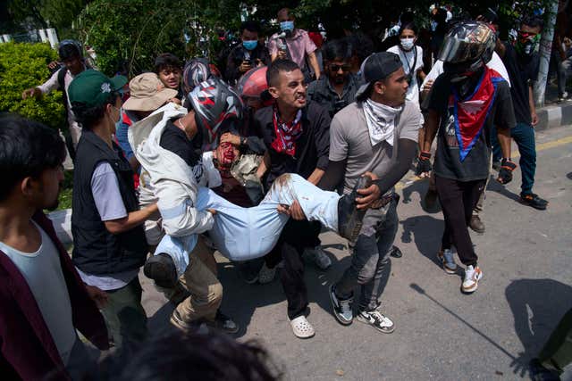 An injured protester is taken to hospital by his friends during a protest in front of the parliament building in Kathmandu