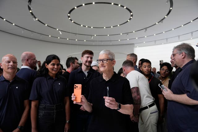 Apple chief executive Tim Cook holds new iPhones handsets
