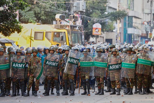 Army soldiers in riot gear stand guard as protesters shout slogans outside the demolished residence of Sheikh Mujibur Rahman, Bangladesh’s former leader and the father of the country’s ousted prime minister Sheikh Hasina following the verdict against her, in Dhaka, Bangladesh 