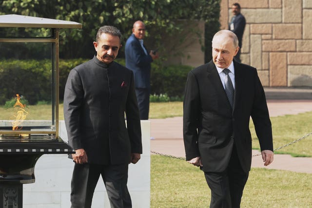 Russian President Vladimir Putin, right, walks after laying a wreath at Rajghat, the Mahatma Gandhi memorial