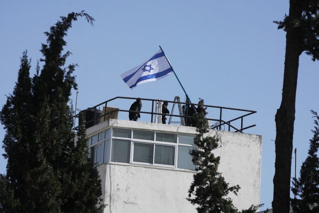 Israeli police and officials erecting an Israeli flag on the compound of the UNRWA