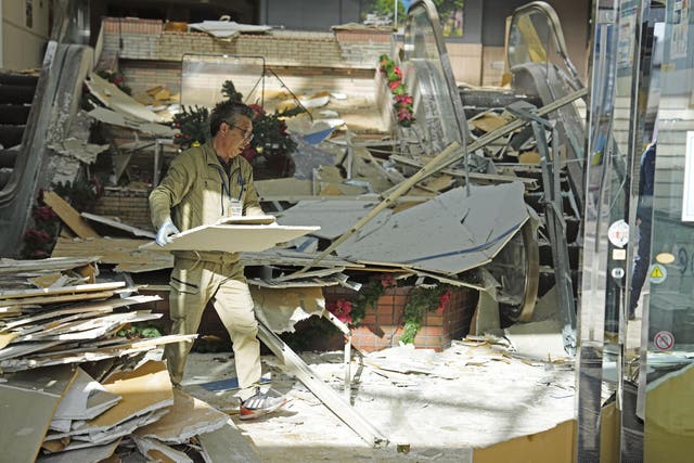 A man clears debris after a powerful earthquake at a commercial facility in Hachinohe, Aomori prefecture, northern Japan