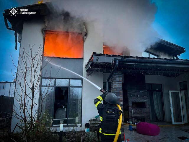 A rescue worker puts out a fire of a residential house destroyed by a Russian strike in Kyiv region, Ukraine