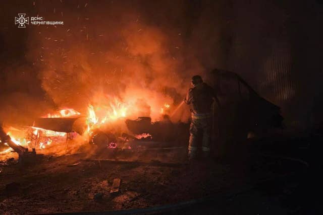 A rescue worker puts out a fire of a car destroyed in a Russian strike in Chernihiv region, Ukraine