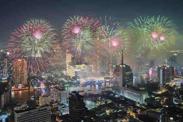 Fireworks explode over a river during celebrations in Bangkok, Thailand 