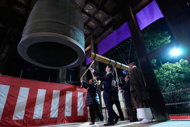 People strike a giant bell to celebrate the new year at the a Buddhist temple in Tokyo