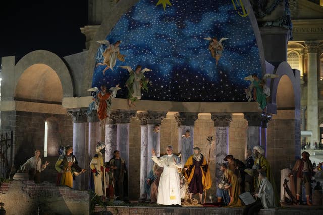 Pope Leo waves after a moment of prayer on New Year's Eve in front of the nativity scene that adorns St Peter’s Square at the Vatican 