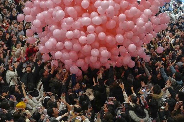 Revellers film and catch falling balloons as they celebrate the start of 2026 in Beijing