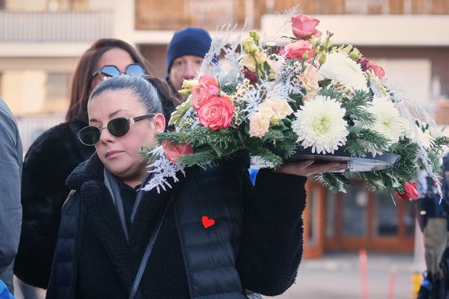 A woman carrying a large floral wreath