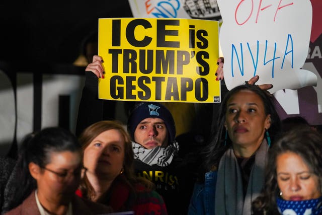 A man among protesters gathered in Minneapolis holding a sign that reads 