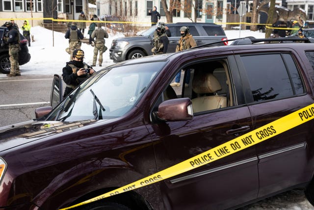 A bullet hole and blood stains are seen in a crashed vehicle cordoned off by yellow police tape at the scene of the shooting