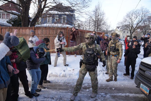 A law enforcement agent spraying a line of protesters with chemical spray at the scene of the shooting