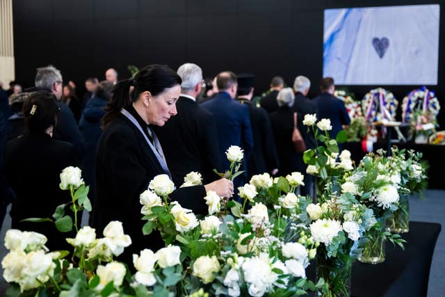 People lay white roses in tribute to the victims 