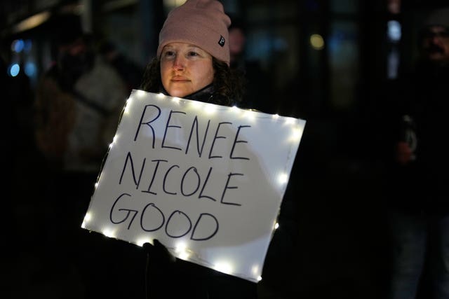 A woman holds a sign in support of Renee Good