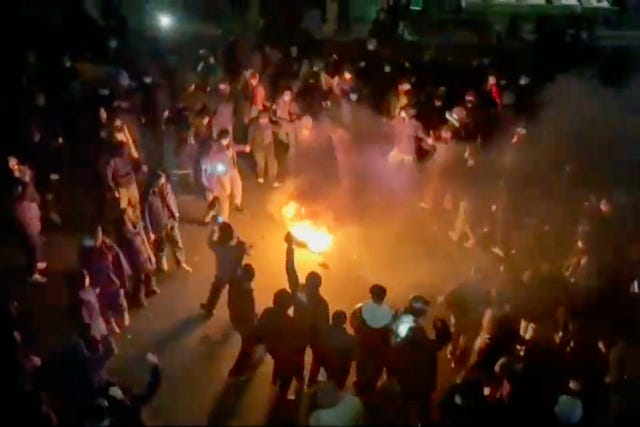 In this frame grab from footage circulating on social media, protesters dance and cheer around a bonfire in Tehran, Iran 