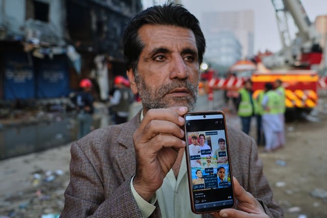 Mahmood Khan showing the press pictures of six family members who he says went missing after the fire