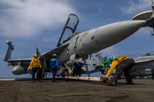 A US fighter jet is prepared on the deck of an aircraft carrier